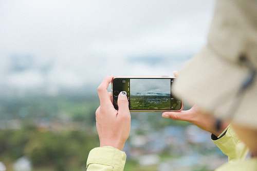 electronics person taking photo of green field mobile phone